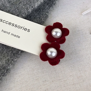 Detail of red velvet flower hair clips with pearl centers on a card holder