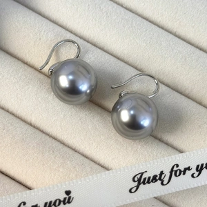 Primer plano de pendientes de perlas gris plata con ganchos de metal pulido fino