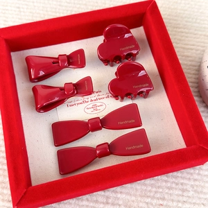 Detalle de pinzas rojas de lazo y corazón con texto Handmade dorado en caja de regalo