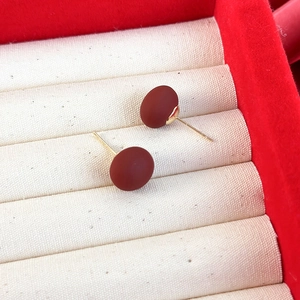 Gros plan de boucles d'oreilles perles ovales rouge mat avec tiges dorées en boîte