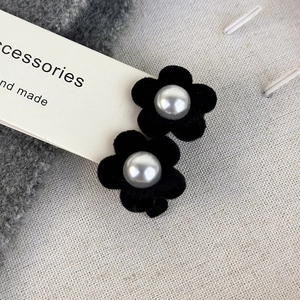 Close-up of velvet flower hair clips with faux pearl center on soft fabric background