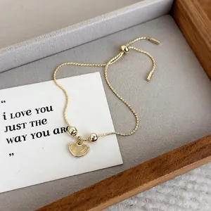 Elegant gold adjustable bracelet with cat eye heart pendant on a wooden jewelry tray
