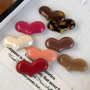 Set of colorful acetate heart hair clips in various patterns on a textured fabric