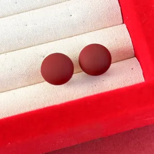 Gros plan de boucles d'oreilles perles rouge mat dans un coffret à bijoux en velours blanc