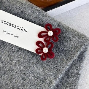 Macro shot of red velvet flower hair clips with white pearls on a grey knitted texture