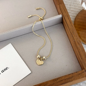 Detail of adjustable gold heart bracelet with cat-eye stone pendant on display tray