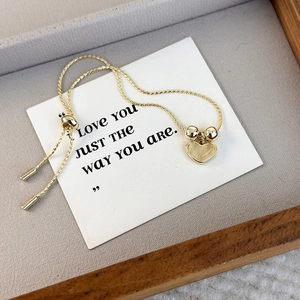 Elegant gold heart pendant bracelet with cat eye stone in a wooden jewelry tray