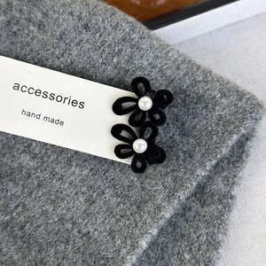 Detail view of handmade velvet flower hair clips with white pearls on a display card