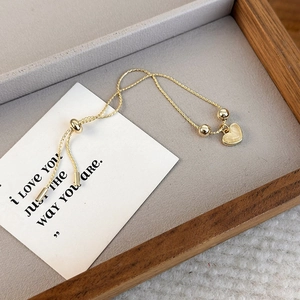 Adjustable gold heart pendant bracelet with cat eye stone bead on velvet tray