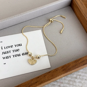 Detail view of a gold heart pendant bracelet with cat eye stone and adjustable slide clasp