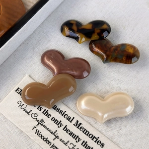Macro shot of five colorful heart-shaped acetate hair clips on vintage canvas