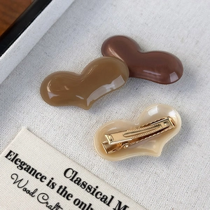 Close-up of heart-shaped acetate hair clips in brown, coffee, and beige colors