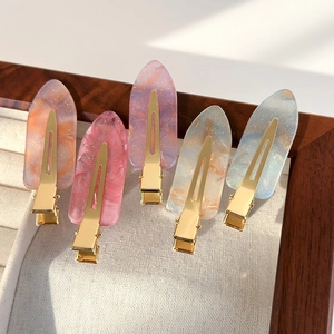 Set de 5 barrettes à cheveux dégradé rose marbré avec base dorée sur un plateau