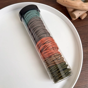 Close-up of multicolored high-elasticity hair ties stored in a transparent cylinder jar