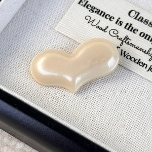 Macro shot of a cream-colored heart-shaped acetate hair clip in a luxury gift box