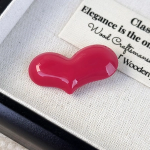 Macro view of a glossy rose red heart hair clip in a black jewelry box with fabric lining