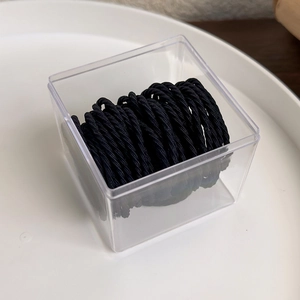 Close-up of black elastic hair ties with ribbed texture in a clear plastic storage box