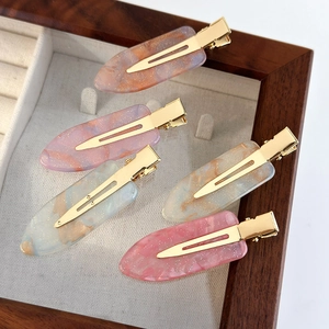 Lot de 5 pinces à cheveux à motif marbré aux tons roses et bleus sur un plateau en bois