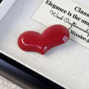Detail shot of a glossy red heart acetate hair clip in a luxury black gift box