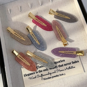 Set of seven elegant glitter hair clips with gold metal base in a jewelry box display