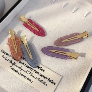 Macro shot of glittery matte hair clips in four colors with gold metal duckbill base