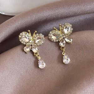 Close-up of gold butterfly earrings with sparkling crystals and a water drop pendant