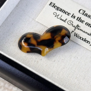 Macro shot of tortoiseshell acetate heart hair clip on beige velvet display background
