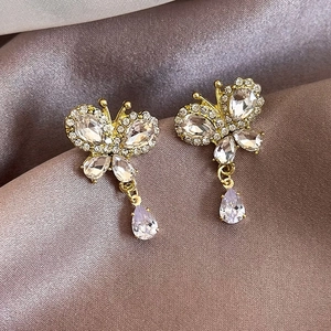 Sparkling butterfly stud earrings with crystal pear drop on elegant silk background