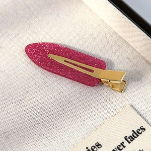 Detailed macro view of the glittery rose pink hair clip with its sturdy golden alloy base