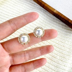 Macro shot of French vintage pearl earrings with zircon halo on gold metal setting