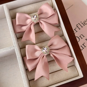 Pink satin bow hair clips with heart gemstone set in a beige velvet jewelry box