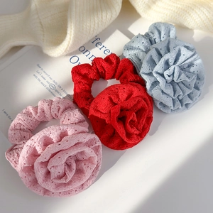 Three large fabric flower scrunchies in pink, red, and blue with eyelet lace details