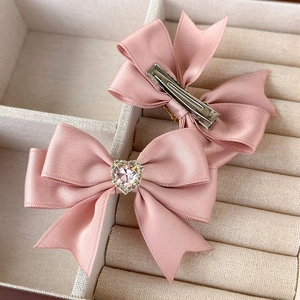Detail of pink satin bow hair clips with heart crystal and silver alligator clasp