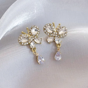Detail of gold butterfly drop earrings with shimmering crystals on a silk background