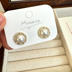 Detailed close-up of French vintage pearl earrings with a sparkling zircon halo and gold base