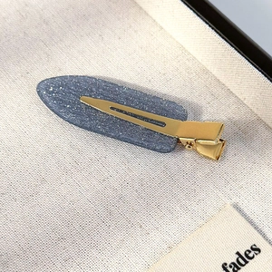Detailed close-up of a blue glitter hair clip with a gold metal duckbill clamp