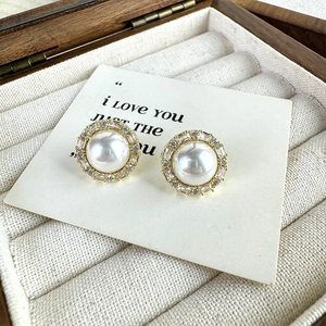 Close-up of French vintage pearl stud earrings with sparkling zircon halo on wood box