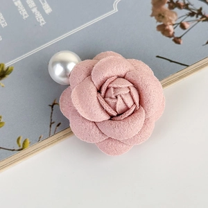Dettaglio macro della molletta a camelia in tessuto rosa con elegante perla