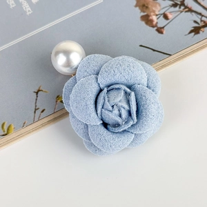 Dettaglio del fermaglio per capelli a camelia in tweed azzurro con perla bianca