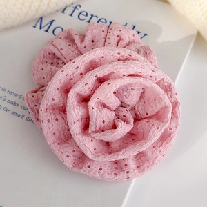 Detailed close-up of pink lace fabric flower scrunchie with intricate eyelet embroidery