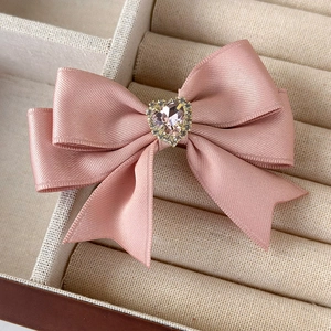 Pink satin bow hair clip featuring a heart-shaped pink crystal with fine diamond border