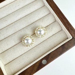 Detail of French vintage pearl earrings with zircon inlay on beige velvet jewelry box