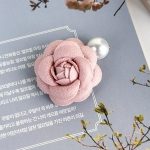 Dettaglio fermaglio per capelli a camelia rosa in tessuto con perla bianca lucida