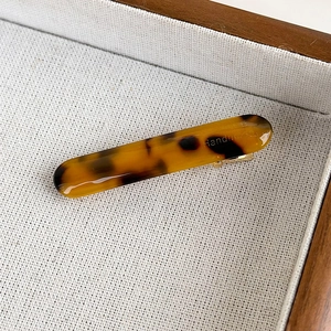 Detailed view of handmade acetate tortoiseshell hair clip on a white textured fabric
