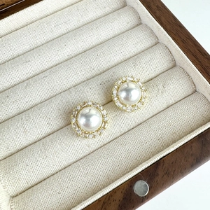 Detail of vintage pearl stud earrings with zircon halo on a wooden jewelry display