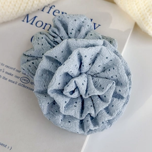 Macro view of light blue floral scrunchie with intricate hollowed knit texture