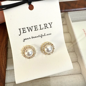 Close-up of elegant French vintage pearl stud earrings with zircon halo on jewelry card