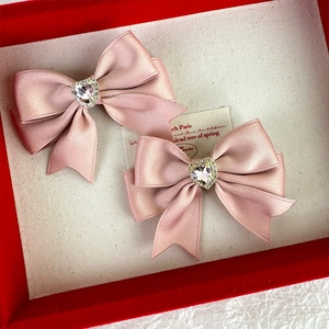 Detail of pink satin bow hair clips with heart-shaped crystal centers and pavé diamonds