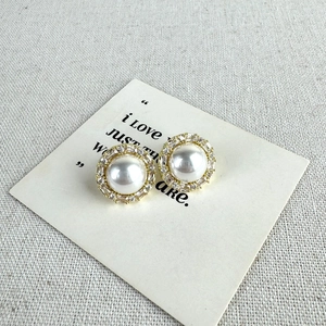 Detailed close-up of French vintage pearl stud earrings with zircon halo on gold plating