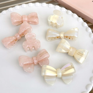 Elegant jelly-colored acetate bow hair clips and mini claw clips on a decorative plate
